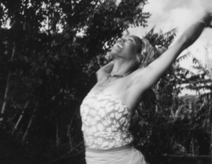 Medium black and white shot of Wyoma in triumphant dance pose, arms up, looking up toward the sky